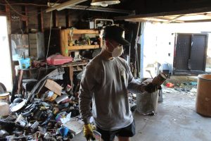 Worker clearing out a severely cluttered garage during a hoarding cleanout in Fontana, CA